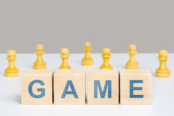 The word game is on wooden cubes among chess pieces of pawns. The concept of team play