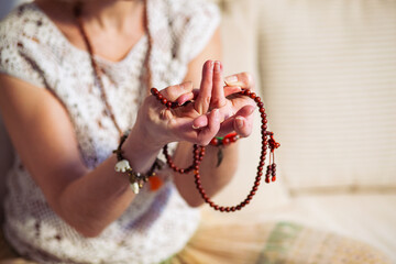 Woman at meditate place in lotus position using Mudra,  hand close up, strands of  beads used for...
