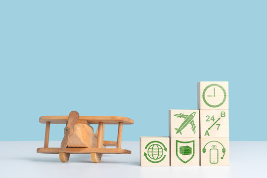 The concept of air transportation, delivery and logistics services. A wooden airplane toy stands at the cubes with information icons. Blue background, copy space