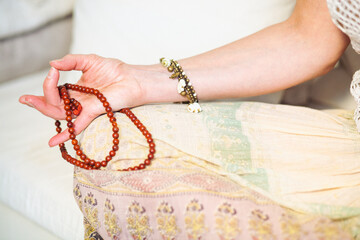 Woman at meditate place in lotus position using Mudra,  hand close up, strands of  beads used for...