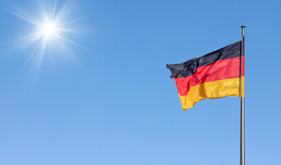 german flag in the wind with blue sky in background