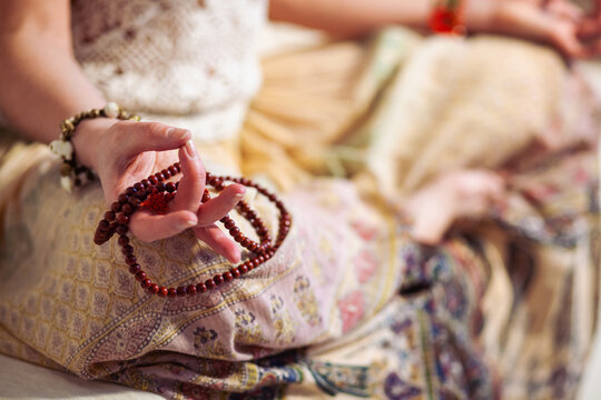 Woman at meditate place in lotus position using Mudra,  hand close up, strands of  beads used for keeping count during mantra meditations