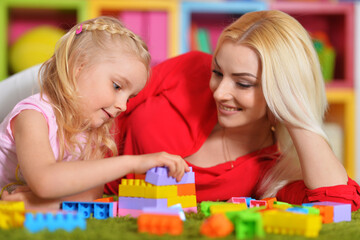 young mother and little daughter playing blocks game