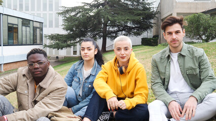 Group of multiethnic student friends sitting in park looking at camera
