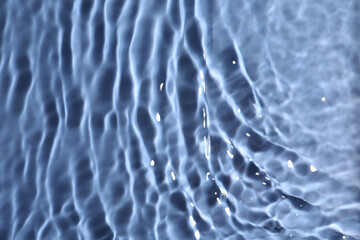 Closeup view of water with rippled surface on blue background