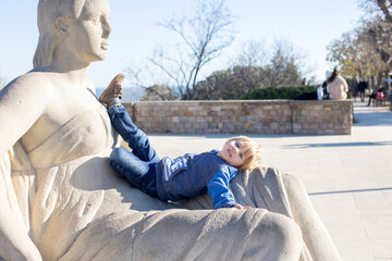 Child, lying on a sculpture in park in Barcelona, Spain. Kid enjoying walk