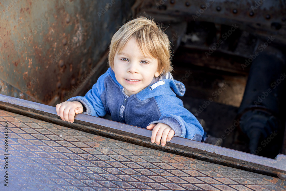 Wall mural Cute little child tourist, admiring Barcelona city, standing in an old tank weapon in front of the castle Montjuic in Barcelona, family travel with kids