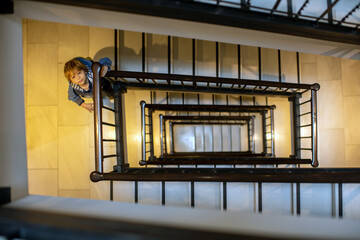 Spiral staircase in a building. Child, standing on the lower floor, looking at camera