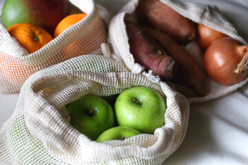 Reusable mesh bags filled with various healthy fruit and vegetable. Selective focus.