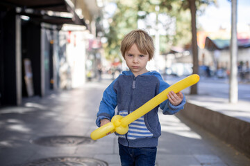 Cute little child tourist, holding balloon made as a sword, admiring Barcelona city, family travel...