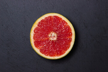 Half of a grapefruit on a black background. Ripe citrus fruit.