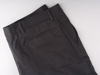 Old black trousers folded in half on a light gray background. Top view