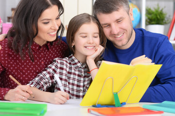 Portrait of parents and daughter doing homework