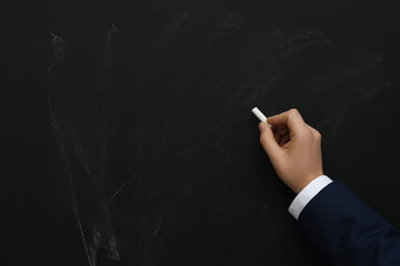 Man with white chalk near blackboard, closeup. Space for text
