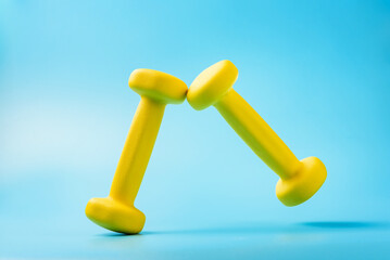 Two yellow dumbbells on a blue background.