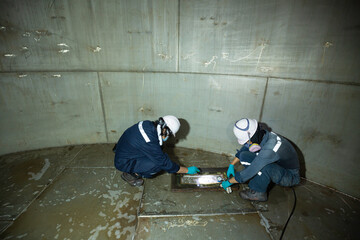 Male worker inspection vacuum test bottom plate tank chemical steel weld leak.