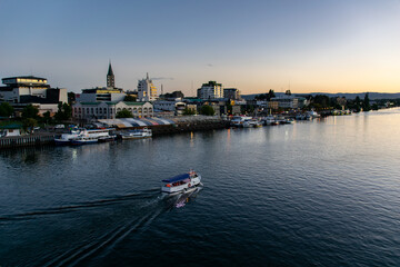 Fototapeta na wymiar a tourism boat sailing across the Calle-Calle river in Valdivia, southern Chile during sunset