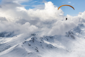 Adventure Composite Image of Paraglider Flying up high in the Rocky Mountains. Cloudy Sky. Aerial...