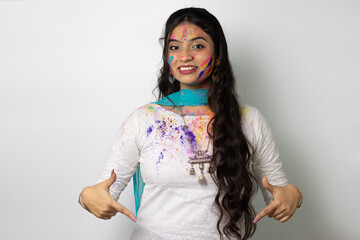 Young indian girl with powder colours on her face for festival of colours Holi, a popular hindu festival celebrated across india, isolated over white background, selective focus advertisement pose