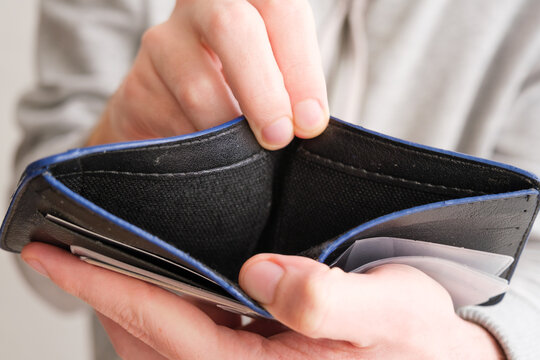 Man Hand Showing An Open Empty Wallet Close Up. Poverty, Cost Control Expenses, Spent Too Much, Not Enough Cash, Lost Money Concept Idea. Top Or Above View.