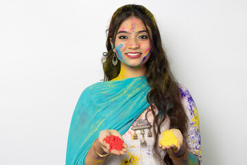 Young indian smart girl with color powder in her hand and with face coloured with gulal for...