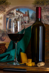 glass and bottle of red wine with hard cheese on urban background, rustic style, low key