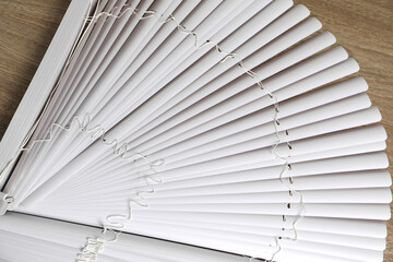 Stylish horizontal window blinds on wooden table, top view