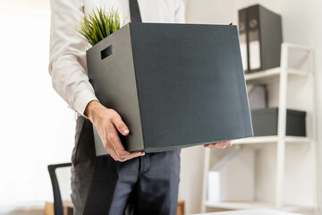 Unemployed, quite job. Desperate caucasian young businessman resigning from company, hand in holding cardboard, packing belongings into box, layoff or changing work. Resignation, employment concept.