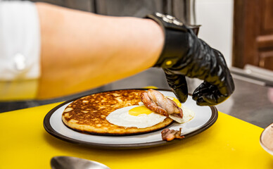 woman Chef cooking fried pancake with mushroom sauce, bacon and egg on kitchen