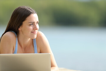 Happy woman with laptop looking at side in nature