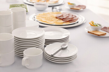 Clean dishware and different meals for breakfast on white table indoors. Buffet service