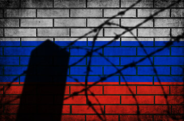 Russian flag with barbed fence. Conflict and war concept. Grunge background texture on brick wall