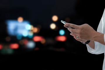 Close-up image of male using smartphone at night on street currently using the phone to chat with friends on social media. The Internet makes communication more comfortable.