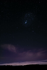 Obraz na płótnie Canvas night starry sky over the forest, sky seen from Poland in February, starry sky and black landscape outline, Sagittarius constellation, purple sky