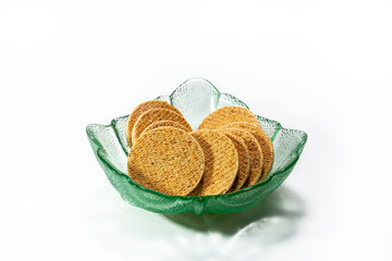 A stack of clotted cream cookies or biscuits in a green decorative glass bowl opn a white background. Cope space