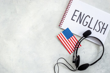 Headpones with notebook on student table desk. Online language courses
