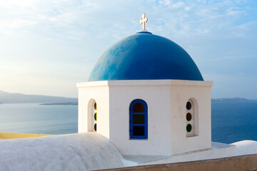 Fototapeta na wymiar White church with blue dome roof overlooking Aegean sea on Santorini, Greece.