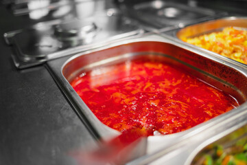 Variety of cooked meals in containers in window of public dining room. Concept of public catering. Delicious borscht. Background.