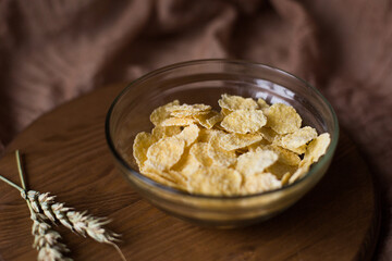 Cornflakes for breakfast on a wooden board and brown background. Morning snack. Food