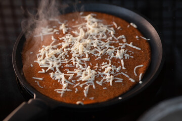 Delicious rosy pancake with melted cheese lies on frying pan. Classic recipe. Traditional homemade cakes. Nutritious breakfast. background.