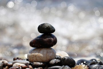 Tower of pebble stones on blurred background of the sea waves. Beach vacation, balance and relax concept