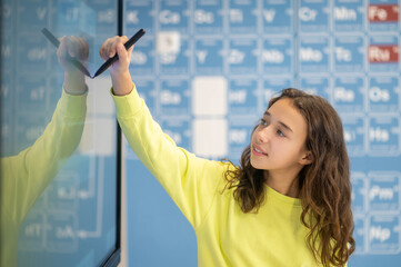 Girl drawing with marker on blackboard in classroom