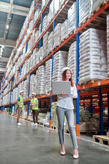 Woman standing working on laptop in warehouse