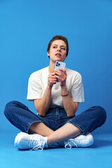 Happy nice girl using cellphone isolated over blue background