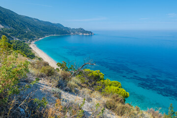 Fototapeta na wymiar Scenic cliffs near sunny sea shore on a bright clear blue day in Greece. Pefkoulia beach with turquoise water and clear blue sky, Lefkada island, Ionian sea coast