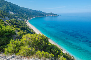 Scenic cliffs near sunny sea shore on a bright clear blue day in Greece. Pefkoulia beach with turquoise water and clear blue sky, Lefkada island, Ionian sea coast
