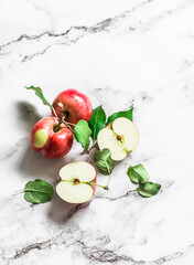 Fresh red small apples with leaves on a marble background, top view