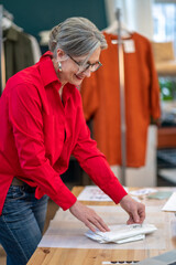 Woman standing sideways to camera touching packaging on table