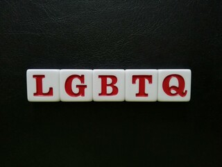 The term LGBTQ is spelled with white and red tiles on a black leather background sheet