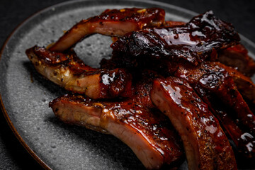 smoked ribs in sauce on a plate on a dark background